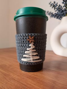 a crocheted coffee cup sleeve with a christmas tree on it