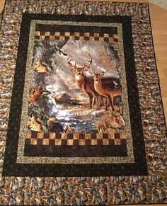 a quilt with two deer on it sitting on top of a wooden floor next to a table