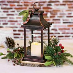 a candle is lit on top of a table with greenery and pine cones around it