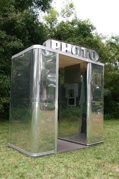 a portable toilet sitting on top of a lush green field in front of some trees