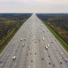 an aerial view of a highway with many cars on it and trees in the background