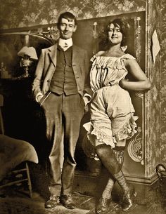 an old photo of a man and woman posing for the camera