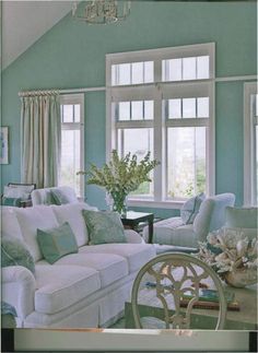 a living room filled with white furniture and blue walls