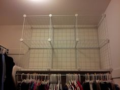 an organized closet with clothes hanging in it