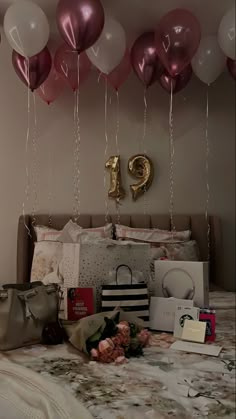 a bed topped with lots of pink and white balloons