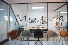 a meeting room with chairs and a table in front of glass walls that say meeting