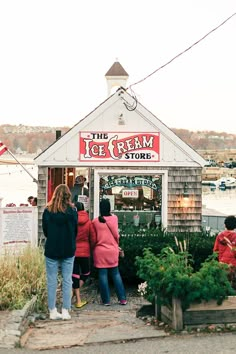 the ice cream store is located in front of some water and people are standing outside