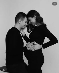 a man and woman standing next to each other with their hands on their stomachs