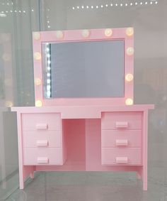 a pink vanity with lights on it in a room