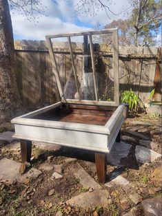 an old bed frame sitting on top of some rocks near a tree in the yard