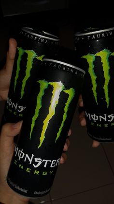 two cans of monster energy drink in their hands