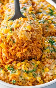 a spoon scooping out some food from a casserole dish with corn on it