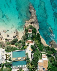 an aerial view of the beach and pool area in front of some rocks, water and trees