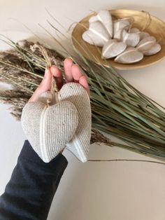 a person holding a heart shaped object in their hand next to some dried grass and other items