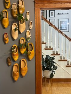 there are many pairs of shoes hanging on the wall next to stairs and potted plants