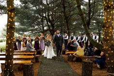 a bride and groom are walking down the aisle with their wedding party in the background