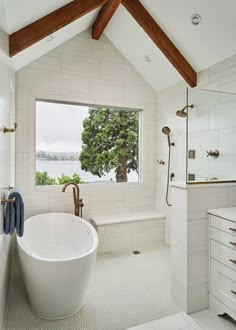 a large white bathtub sitting under a window in a bathroom next to a sink