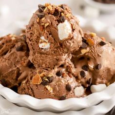 three scoops of ice cream in a white bowl with chocolate chips and marshmallows