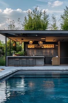 an outdoor bar next to a pool with blue water and trees in the back ground