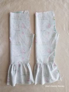 two pieces of white fabric with pink flowers on them, one piece has ruffles