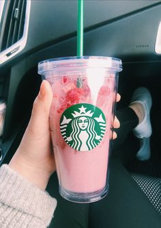 a person holding up a starbucks cup with strawberries in it and a green straw