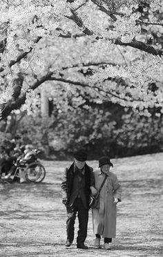 a man and woman standing under a tree in black and white with flowers on it