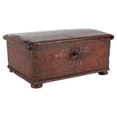 an old wooden trunk with writing on it's lid and handle, sitting against a white background