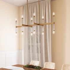 a dining room table and chairs with a wooden bowl on the centerpiece, in front of a curtained window