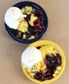 two bowls filled with fruit and ice cream on top of a brown cloth covered table