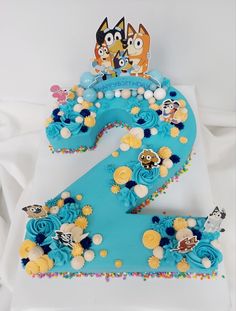 the number two is made up of blue frosting and decorated with cartoon characters on it