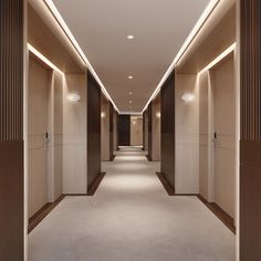 an empty hallway with lights on the ceiling and walls in front of it is lit by recessed lighting