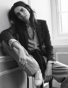 black and white photograph of a woman sitting on a chair with her feet up against the wall