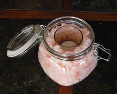 a glass jar filled with lots of pink sea salt sitting on top of a wooden table