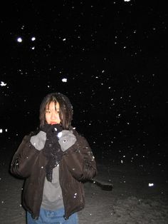 a person standing in the snow at night with their hands on their face and mouth open