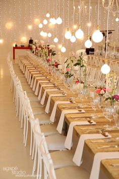 the long table is set up with white chairs and place settings for guests to sit at