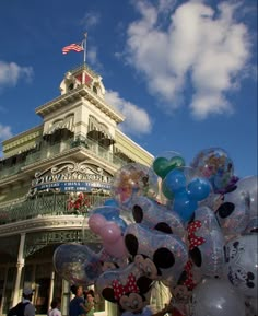 many balloons in front of a building with a flag on top