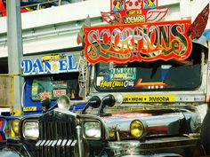 an old truck parked in front of a building with neon signs on it's side