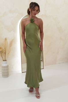 a woman standing in front of a mirror wearing a green dress with a flower on it