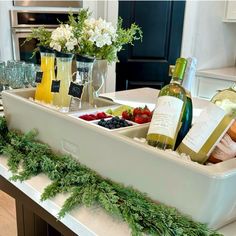 two trays filled with wine, fruit and cheese on a kitchen counter next to flowers