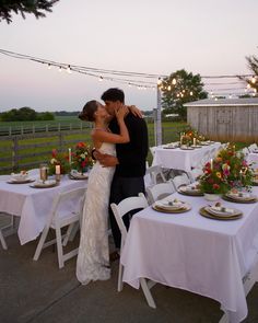 a bride and groom kissing in front of an outdoor dinner table