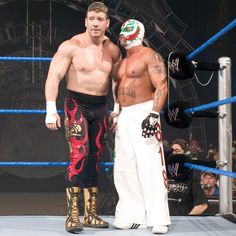 two men standing next to each other in front of a crowd with wrestling gear on