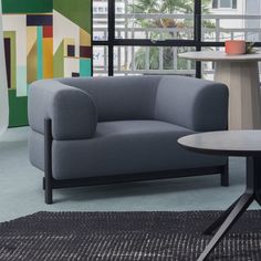 a grey couch sitting next to a table on top of a blue carpeted floor