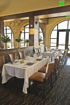 a dining room with tables and chairs set up for an elegant meal in front of large windows