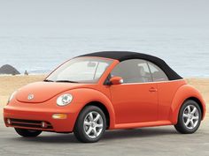 an orange car is parked on the beach