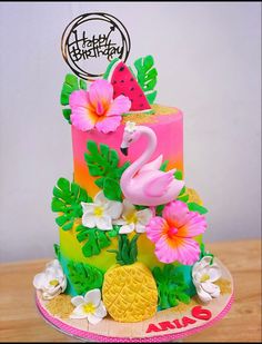 a colorful cake with flamingos, pineapples and flowers