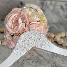 a bridal bouquet with pink flowers and pearls on the hanger, sitting on a marble surface