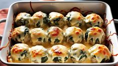 a casserole dish filled with meatballs covered in cheese and spinach sauce