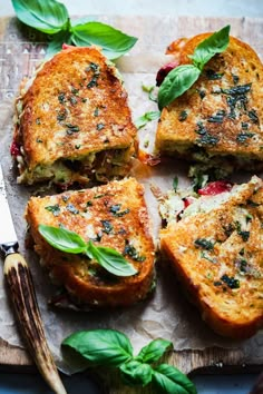 grilled cheese sandwiches with basil leaves and spices on a cutting board next to a knife