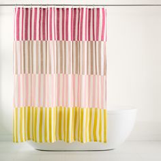 a bathroom with a white toilet and a shower curtain in the shape of strips of different colors