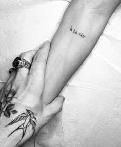 two hands holding each other with tattoos on them